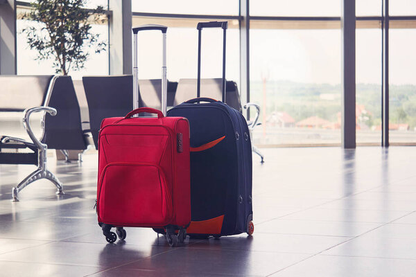 два чемодана лежат на полу в аэропорту. 