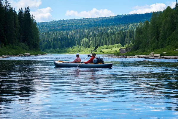 乘双座皮划艇沿河在群山中游览的一对夫妇 — 图库照片