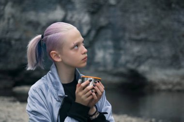 Genç bir kızın portresi nehir kıyısındaki kayalara bakan bir kupayla dinleniyor.