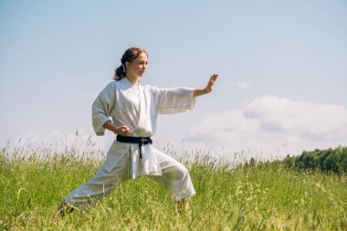 Genç kız dışarıda karate yapıyor.
