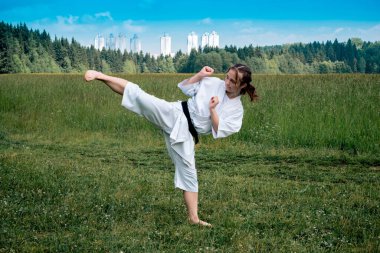 Genç kız dışarıda karate yapıyor, kıro geri kick yapıyor.