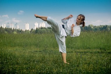 Genç kız dışarıda karate yapıyor, Uro mawashi geri (kanca tekme) yapıyor.)