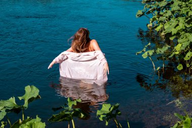 Nehirde yıkanan mutlu genç kadın serin suyun tadını çıkarıyor.