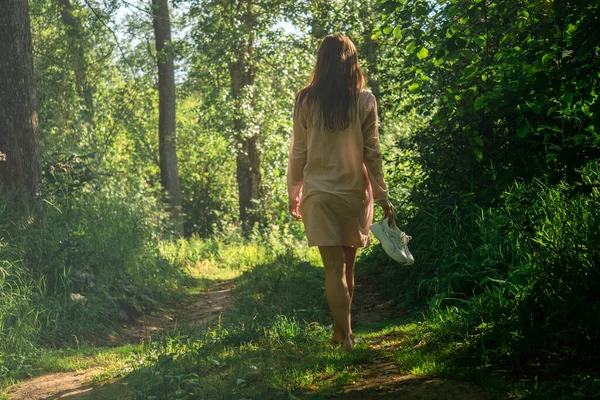 年轻女子在河里游泳后赤脚沿着森林路走着 — 图库照片