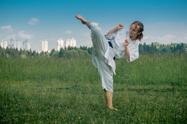 Genç kız dışarıda karate yapıyor, Uro mawashi geri (kanca tekme) yapıyor.)