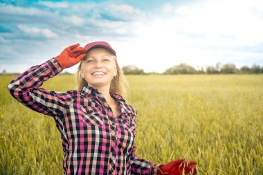 Bir buğday tarlasının arka planında gülen kadın tarım işçisi 