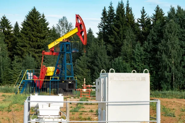 oil pumping station with pumpjack in a clearing in the forest