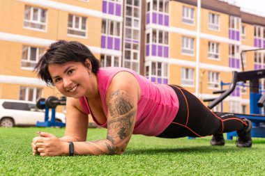 Spor alanında egzersiz yapan kaslı, tombul bir kadın.