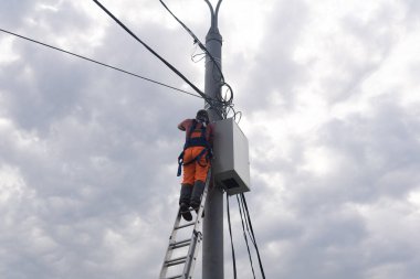 Perm, Rusya - 25 Ağustos 2021: Elektrikçi ya da haberleşme hattı çalışanı telefon direğinin tepesine kablo döşeme üzerinde çalışıyor