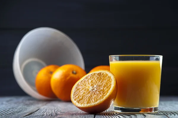 Sumo de laranja fresco e laranjas na mesa de madeira . — Fotografia de Stock