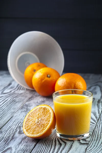 Sumo de laranja fresco e laranjas na mesa de madeira . — Fotografia de Stock