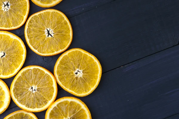 Plasterki pomarańczy na ciemnym niebieskim tle drewniane — Zdjęcie stockowe