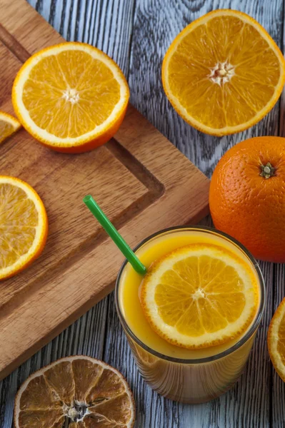 Copo de suco de laranja fresco e laranjas na mesa de madeira . — Fotografia de Stock