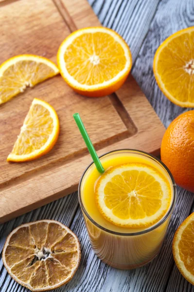 Copo de suco de laranja fresco e laranjas na mesa de madeira . — Fotografia de Stock