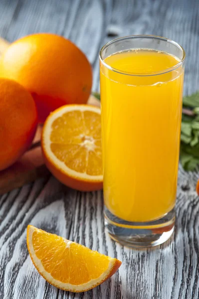 Suco de laranja, fatias de frutas e folhas de hortelã na mesa de madeira — Fotografia de Stock