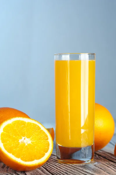Sumo de laranja fresco com laranjas maduras na mesa de madeira — Fotografia de Stock