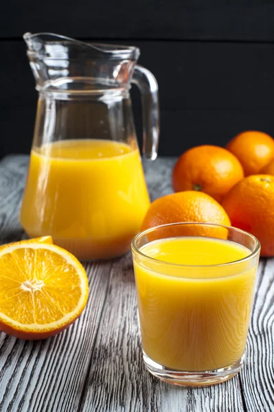 Sumo de laranja fresco, jarro e laranjas maduras — Fotografia de Stock