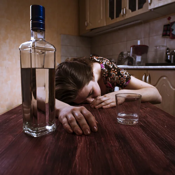 Mujer borracha durmiendo en la mesa en la cocina — Foto de Stock