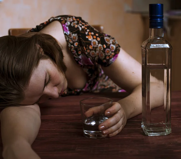 Drunk woman holding her alcoholic drink and sleeping on the tabl Royalty Free Stock Images