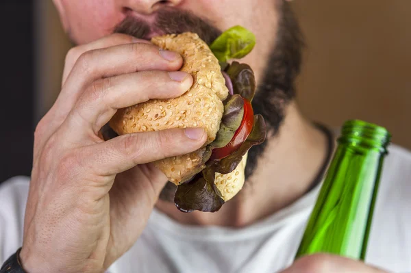 Hombre barbudo con perrito caliente y cerveza —  Fotos de Stock