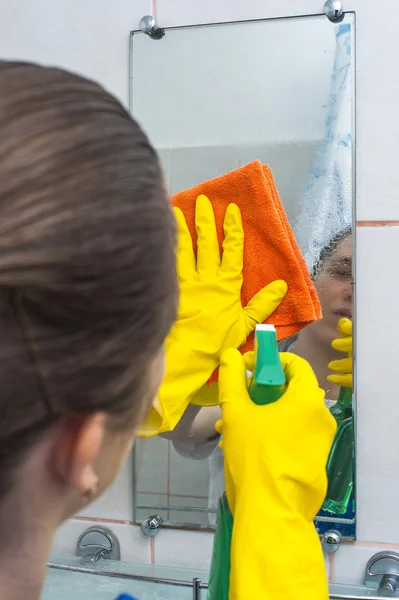 Mujer Yong limpiando el espejo con trapo y spray — Foto de Stock