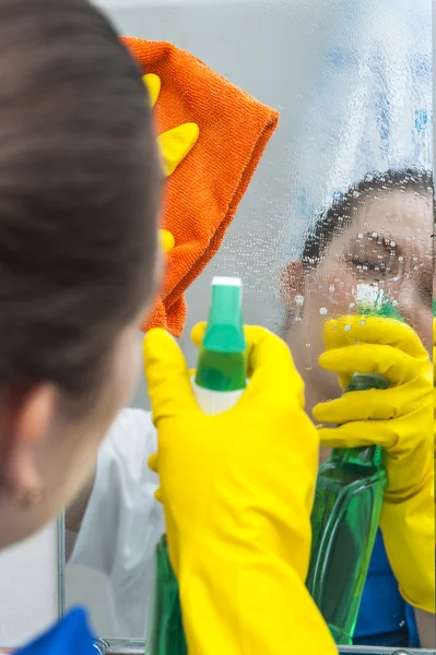 Mujer limpiando un espejo con trapo y spray — Foto de Stock