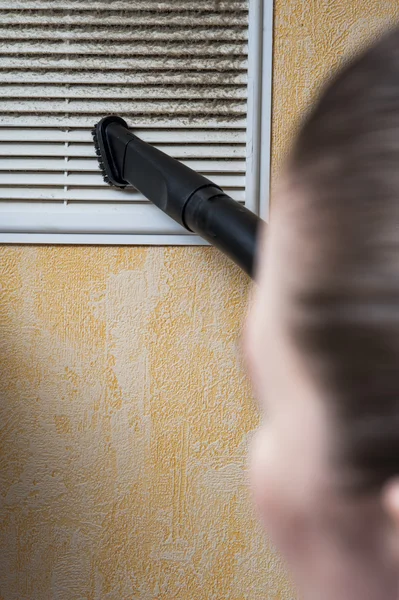 Mujer limpieza ventilación parrilla con aspiradora . — Foto de Stock
