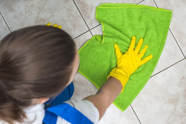 Žena v pracovní oděvy, mytí podlah s zeleným hadr — Stock fotografie