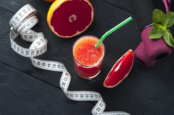 Grapefruit juice, measuring tape and dumbbells — Stock Photo, Image