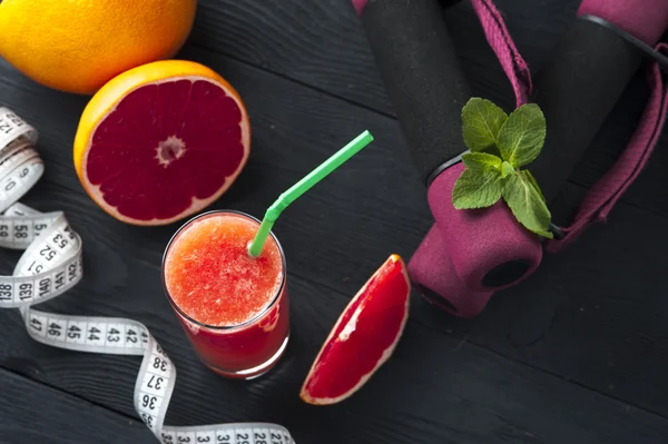 Стакан детоксикационного грейпфрутового сока, гантели и измерительная лента — стоковое фото