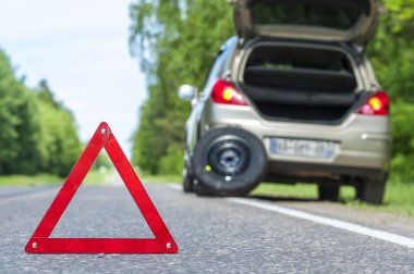 Kırmızı uyarı işareti ve yol kenarı kırık araba