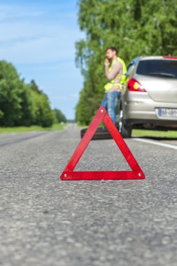 Yol, sürücü ile telefon ve kırık araba acil işareti