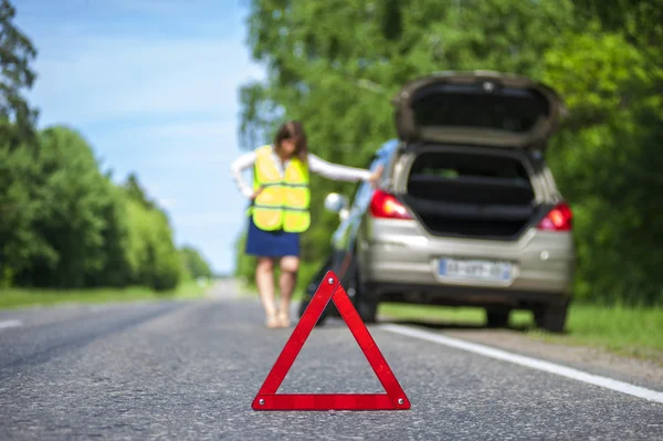 Frau in Warnweste neben kaputtem Auto — Stockfoto