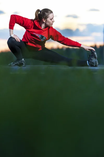 Sporty woman stretching her legs after workout — Stock Photo, Image