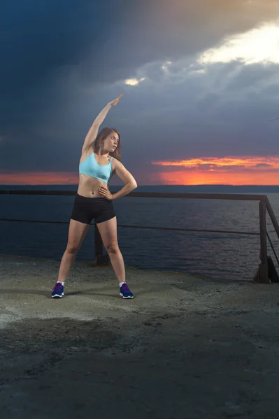 Young woman warming up on pier — Stock Photo, Image