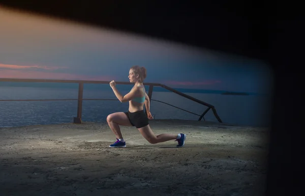 Genç kadın deniz iskelede günbatımında egzersiz — Stok fotoğraf