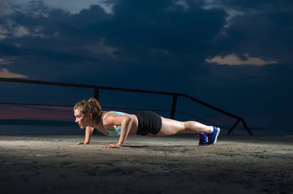 Strong fit woman doing push ups on sea pier — Stock Photo, Image