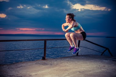Rıhtımda plyometric egzersizleri yapıyor güçlü genç kadın