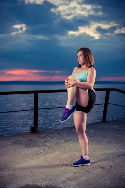 Fit caucasian woman warming up on sea pier — Stock Photo, Image