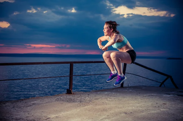 Rıhtımda plyometric egzersizleri yapıyor güçlü genç kadın