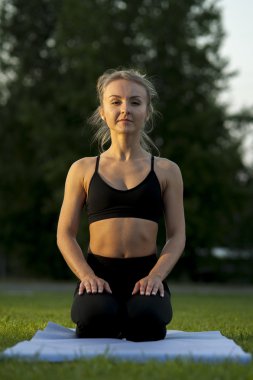 Yeşil çimenlerin üzerinde yoga yaparken sakin sarışın kadın