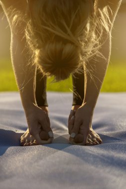 Sarışın yoga kadının mat açık havada egzersiz yapması