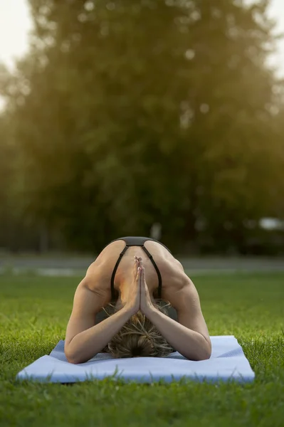 Blond kvinna gör yogaövningar på grönt gräs — Stockfoto