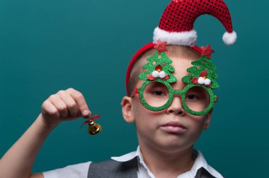 Noel Baba şapkalı küçük mutlu çocuk portresi ve Noel oyuncaklarıyla komik gözlükler.