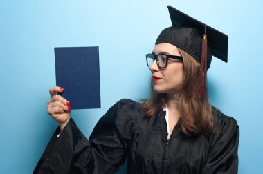 Siyah pelerinli, gözlüklü, gülümseyen çekici bir bayan öğrenci.