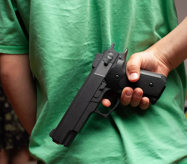 Ragazzino che indossa t-shitr e jeans con pistola alle spalle. — Foto Stock