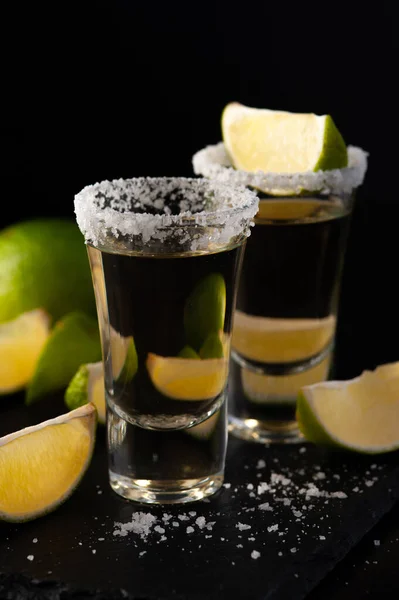 Colpi di tequila messicana d'oro con fette di lime e sale. Fotografia Stock