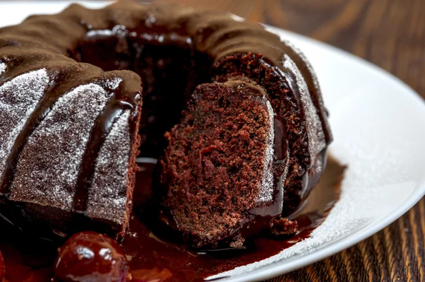 Bolo de chocolate com esmalte, cereja na placa branca — Fotografia de Stock