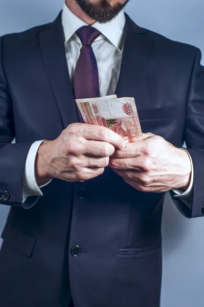 Bebaarde man in pak houdt Russische roebels — Stockfoto