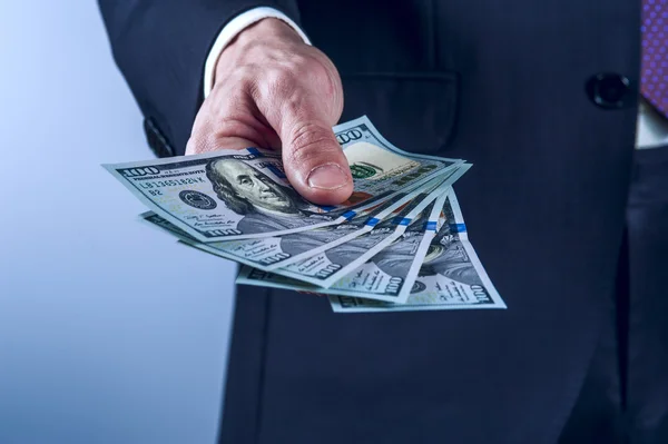 Elbiseli adam bizi gri arka plan üzerinde dolar tutar